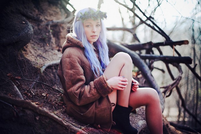 Woman with blue hair and flower crown sitting outdoors