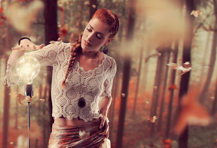 Redhead woman with lightbulb in forest