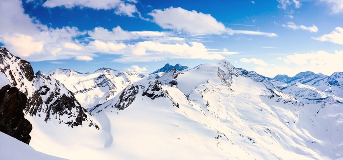 Snowy mountains in Austria under a blue sky with clouds