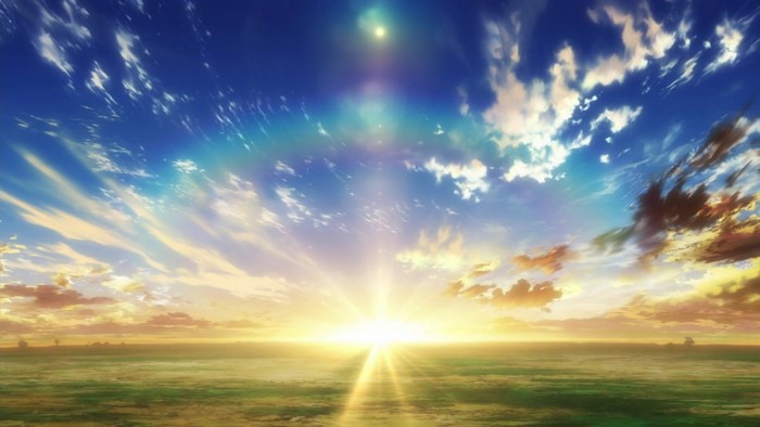 Sunrise over a grassy field with dramatic clouds