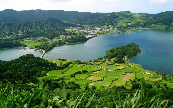 Volcanic lake with a bridge and green landscape