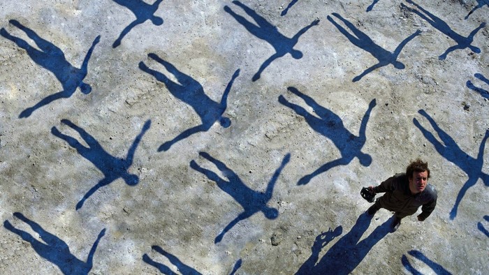 Man standing among shadows of people