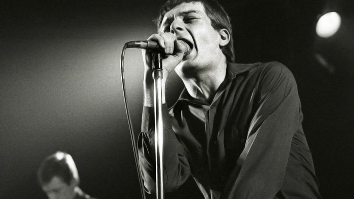 Ian Curtis of Joy Division singing into a microphone