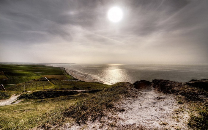 Coastal landscape with sun over the sea