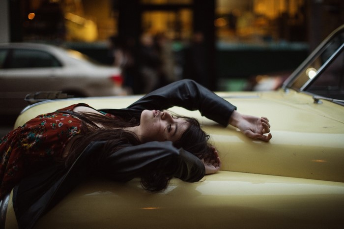 Woman lying on a yellow car hood