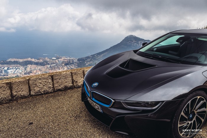 Black BMW i8 parked on a mountain road overlooking Monaco