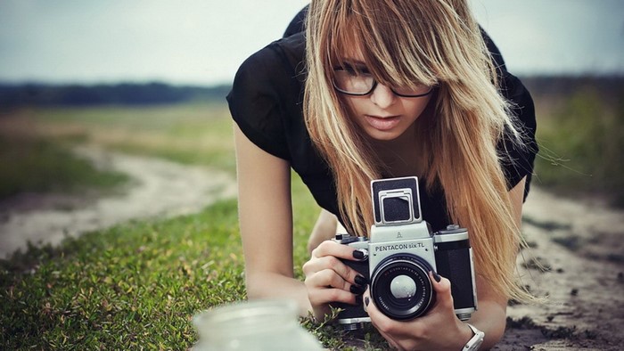 Woman with glasses holding a Pentacon Six TL camera