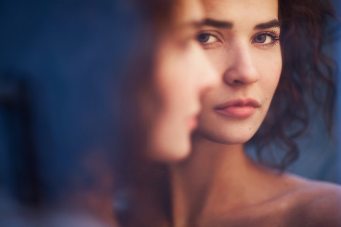Woman looking at her reflection in a mirror
