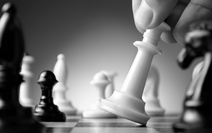 Close-up of a hand moving a white chess piece on a chessboard