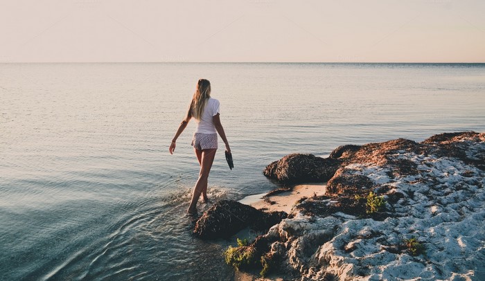 Woman walking into the sea at sunset