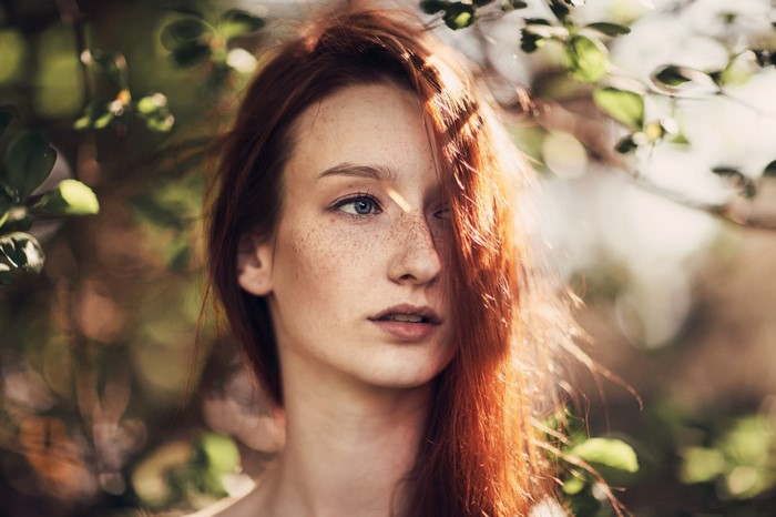 Woman with red hair and freckles in nature