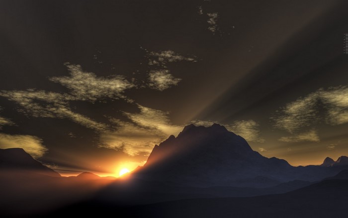 Sunlight rays piercing through clouds over mountains at sunset