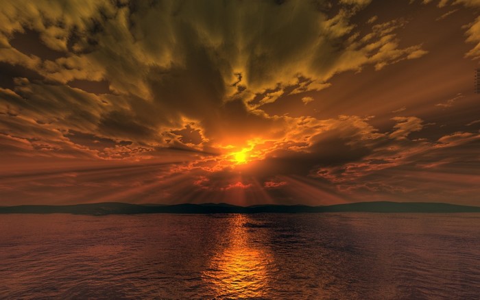 Sunset over the ocean with dramatic clouds and sun rays