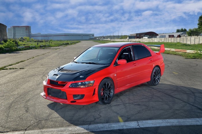 Red Mitsubishi Lancer Evolution with black hood on track