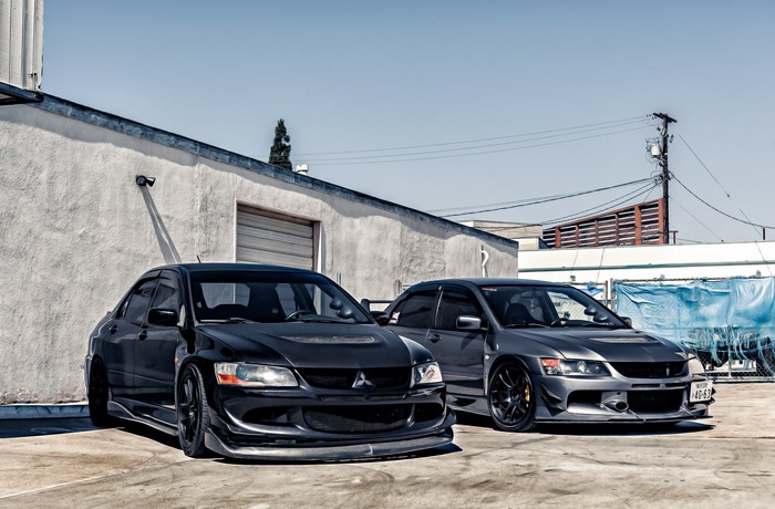 Two Mitsubishi Lancer Evolution cars parked outside a building