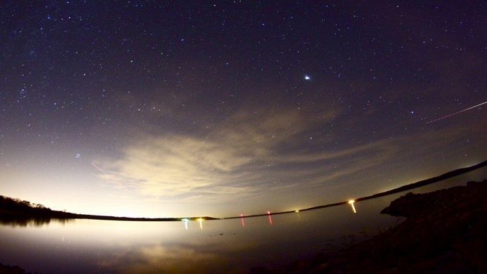 Night sky over a lake with stars and lights