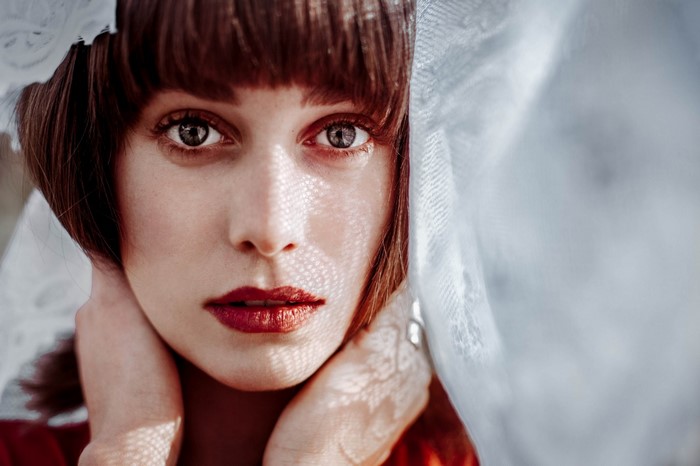 Woman with red lipstick and bangs peeking through lace