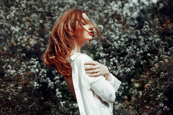 Woman with red hair in an open white shirt