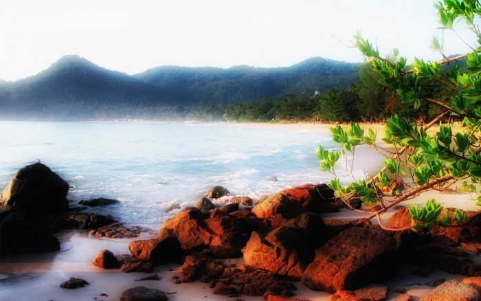 Rocky beach with mountains and sea at sunrise