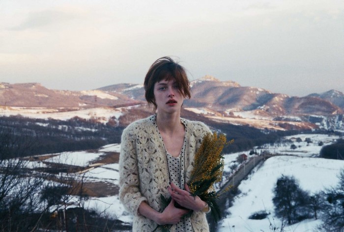 Woman holding flowers in a snowy mountain landscape