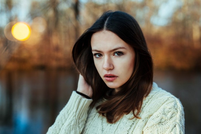 Woman with long brown hair wearing a white sweater