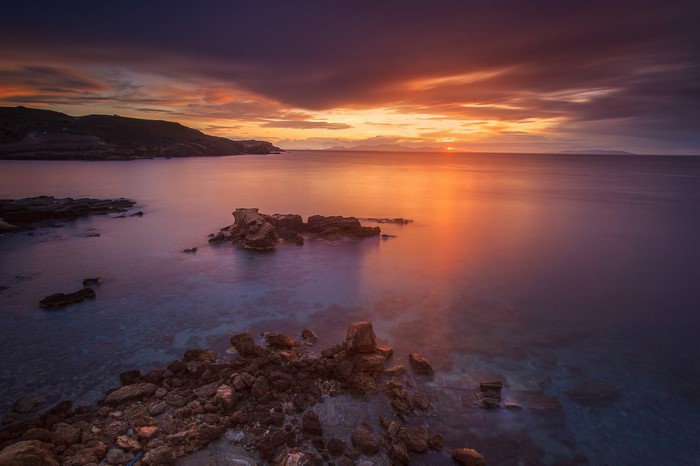 Sunset over the sea with rocky coast