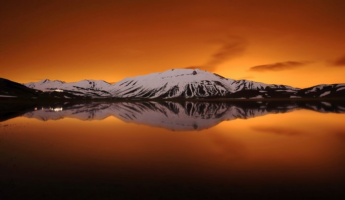 Snowy mountains reflected in a lake at sunset
