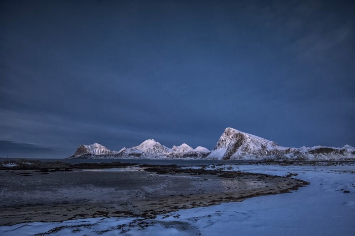 Snow-covered mountains and sea at dusk