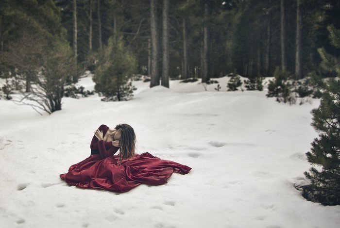 Woman in red dress sitting in the snow