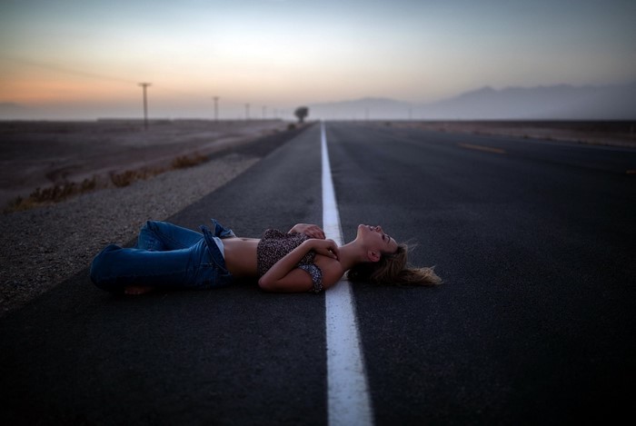 Woman lying on a road at sunset