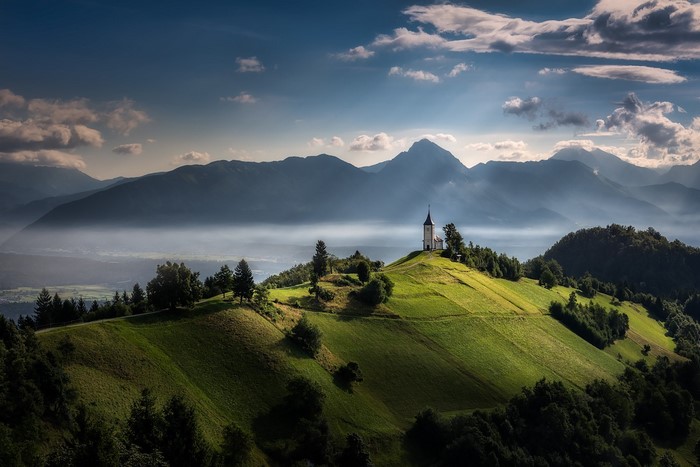 Sunlit Hill with Church in Slovenian Alps