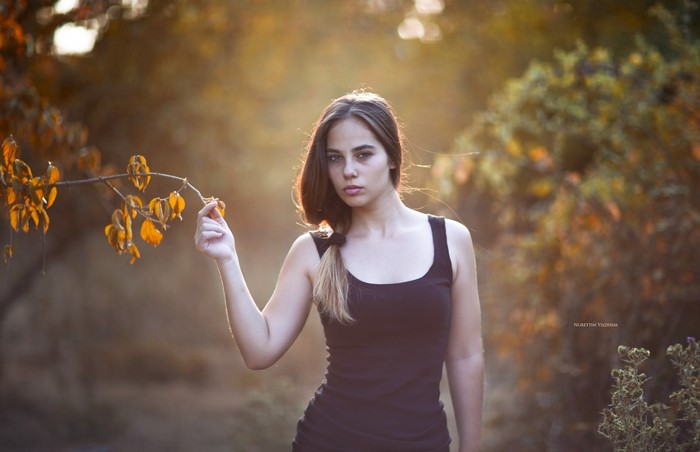 Woman holding a branch with autumn leaves