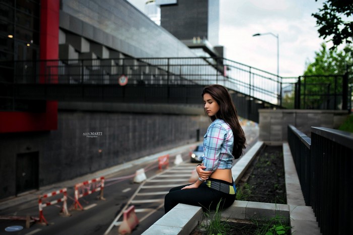 Woman sitting on a ledge by a road