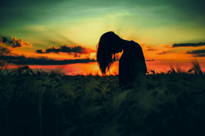 Silhouette of a woman in a field at sunset