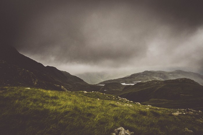 Misty mountains and grassy hills under a cloudy sky