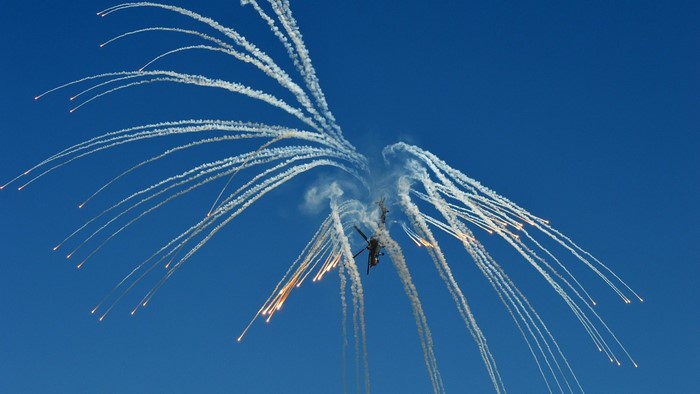 Helicopters performing aerial maneuvers with flares