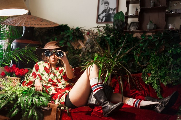 Woman in hat with binoculars surrounded by plants