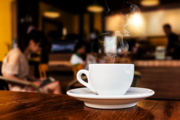 Hot coffee cup with steam in a cafe