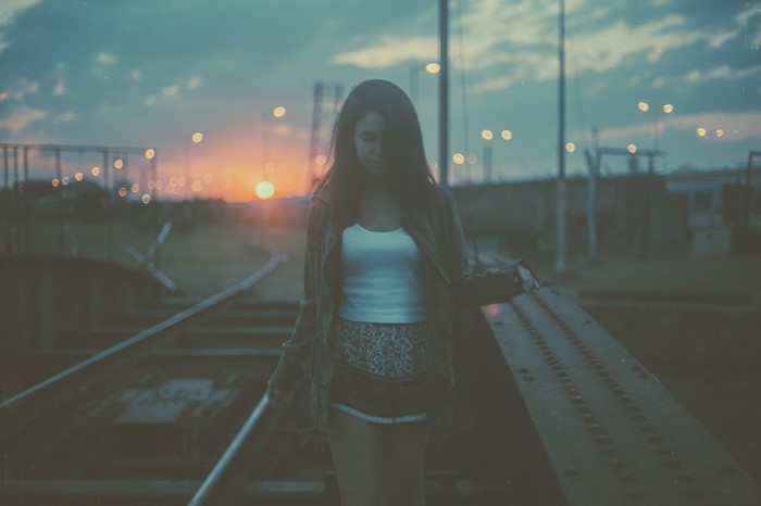 Woman on train tracks at sunset