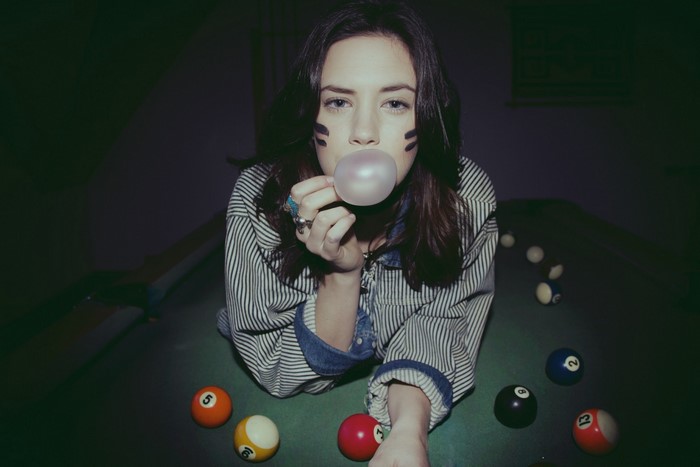 Woman blowing bubble gum on pool table