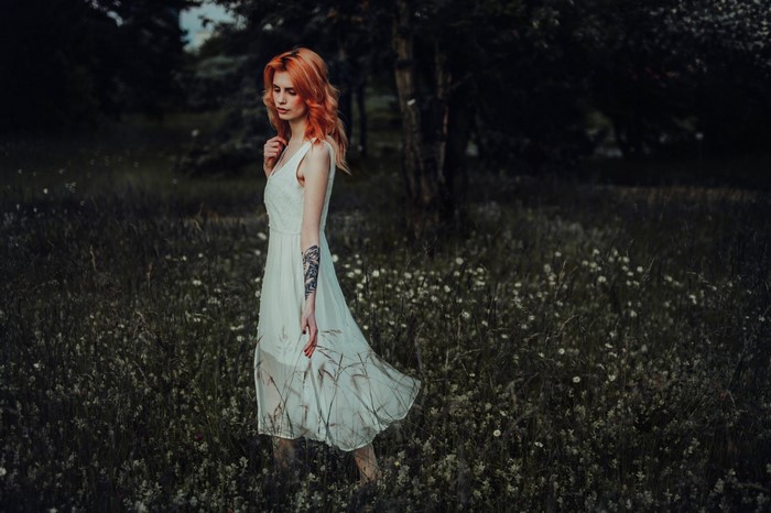 Woman with dyed hair in a white dress in a field