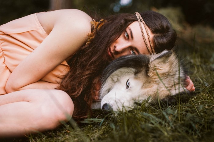 Woman with wolf mask lying in grass