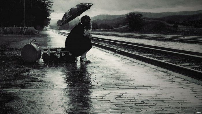 Woman with umbrella and luggage at train station in rain