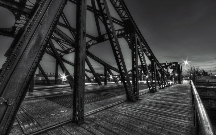 Monochrome view of a steel truss bridge at night