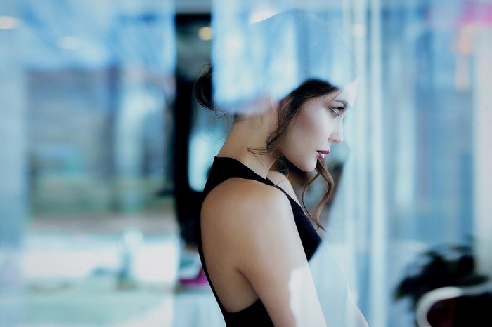 Woman in black dress looking out a window
