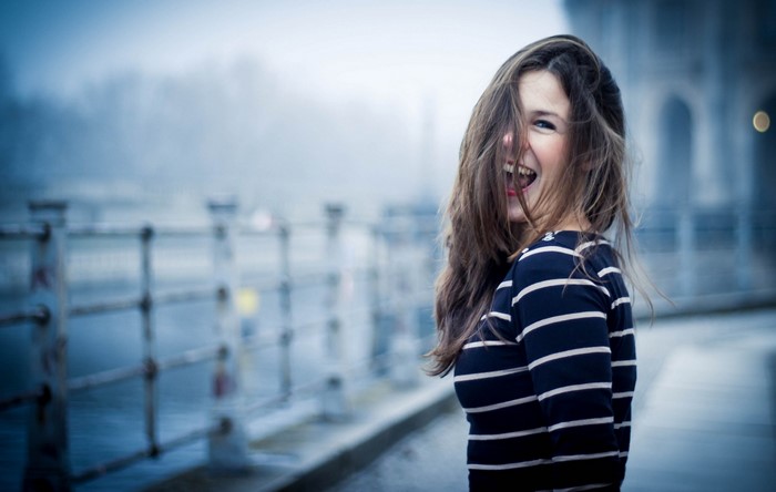 Woman with hair in face laughing outdoors