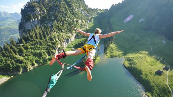 Man bungee jumping over a lake in the mountains