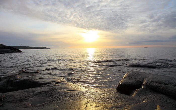 Sunset over a rocky shore and calm sea