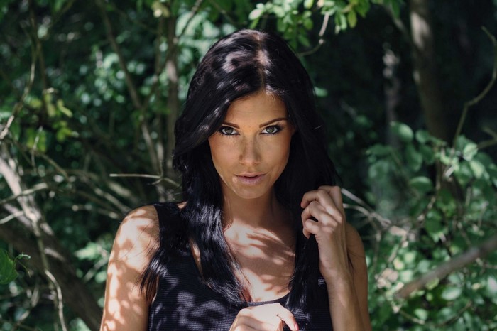 Woman with black hair and green eyes in dappled sunlight