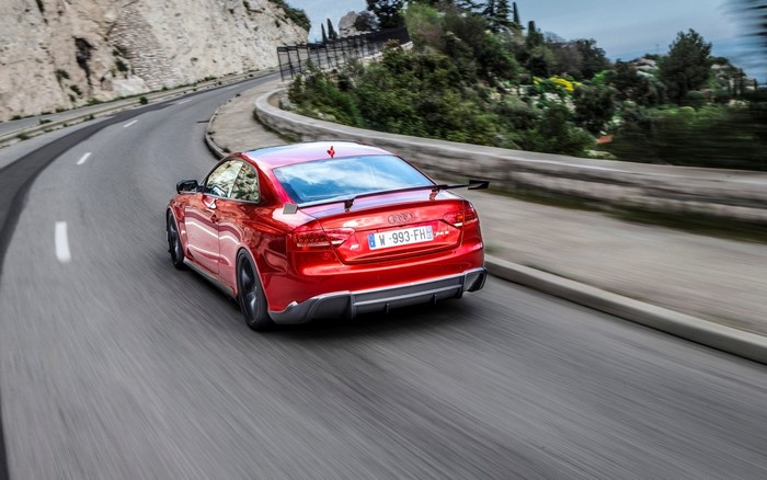 Red Audi RS5 driving on a winding road